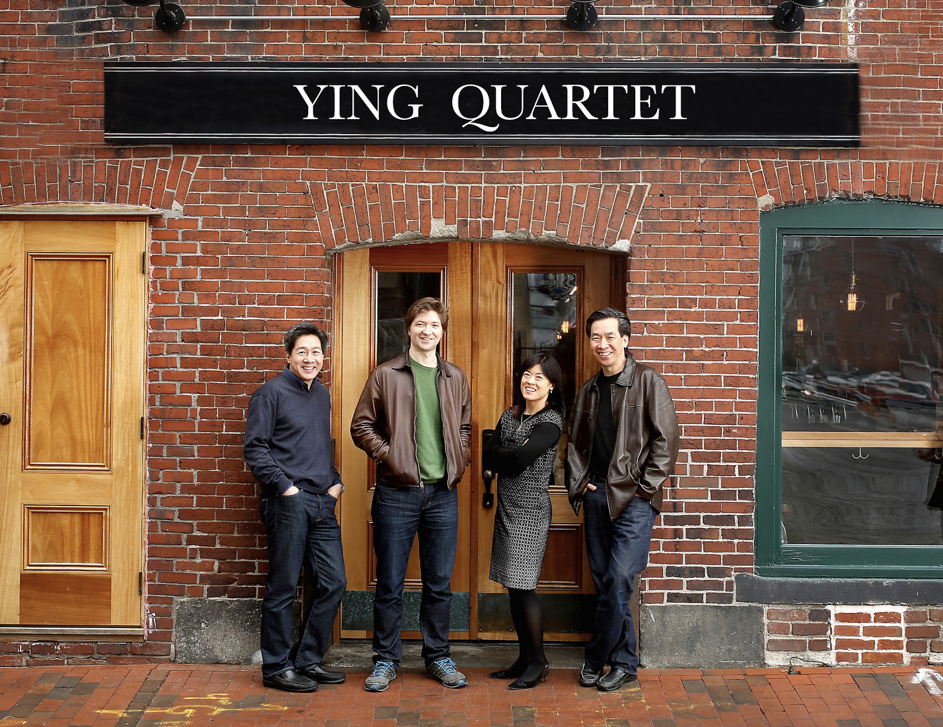 Ying Quartet member smiling against a brick wall